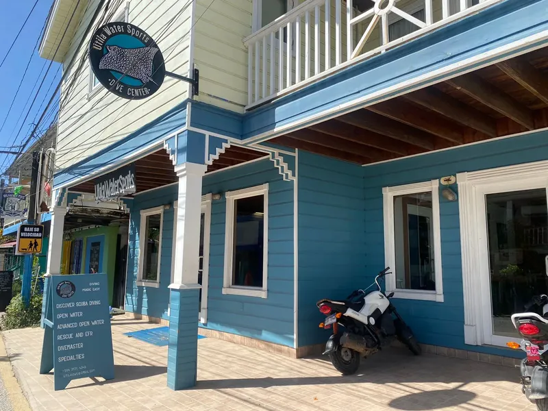 Façade d'un centre de plongée bleu turquoise avec enseigne et scooter