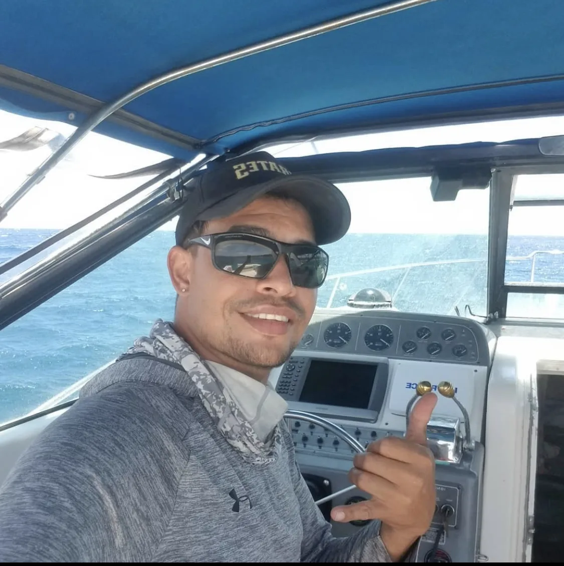 Homme souriant sur un bateau de plongée, pouce levé, en mer