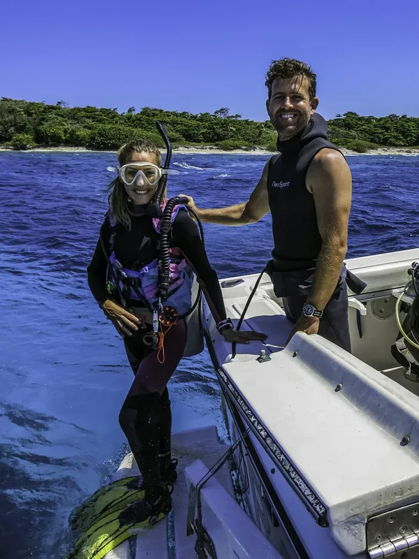 Deux plongeurs souriants sur un bateau en mer, équipement visible