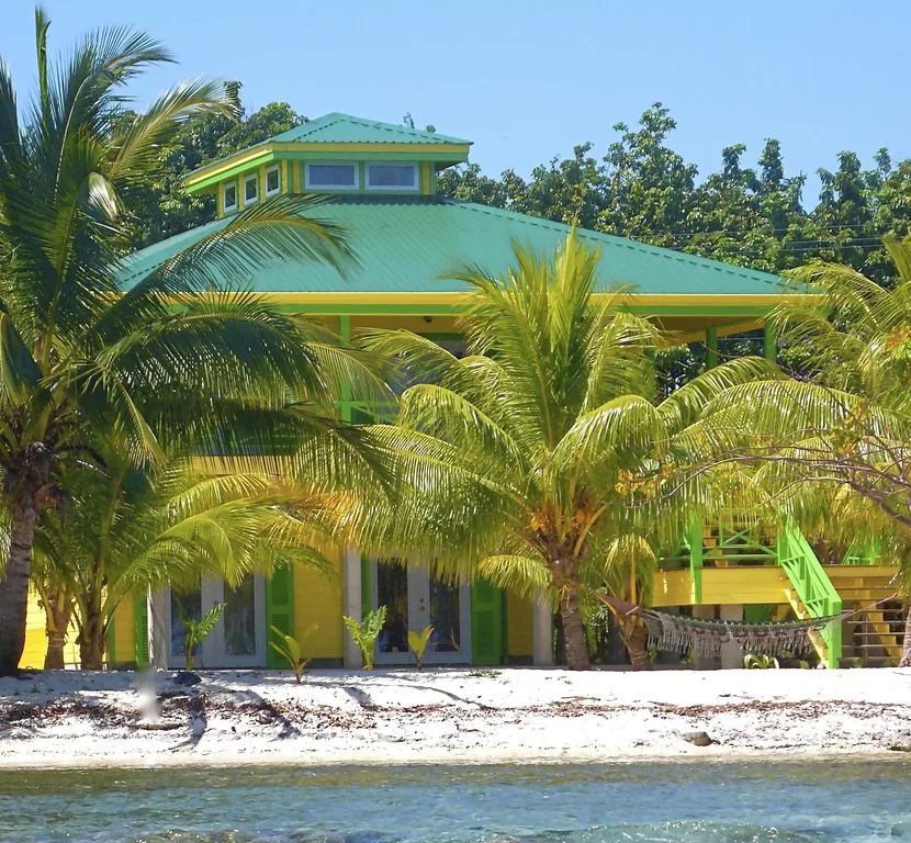 Bâtiment coloré au bord de l'eau, entouré de palmiers et de végétation