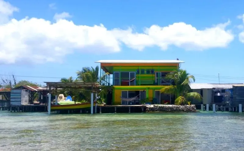 Bâtiment coloré sur pilotis au bord de l'eau avec un bateau
