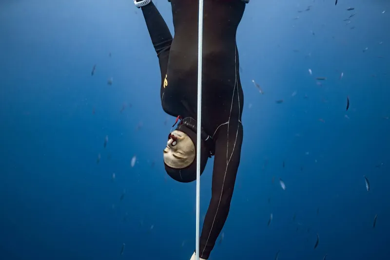 Apnée : une plongeuse descend le long d'un câble vertical dans l'eau