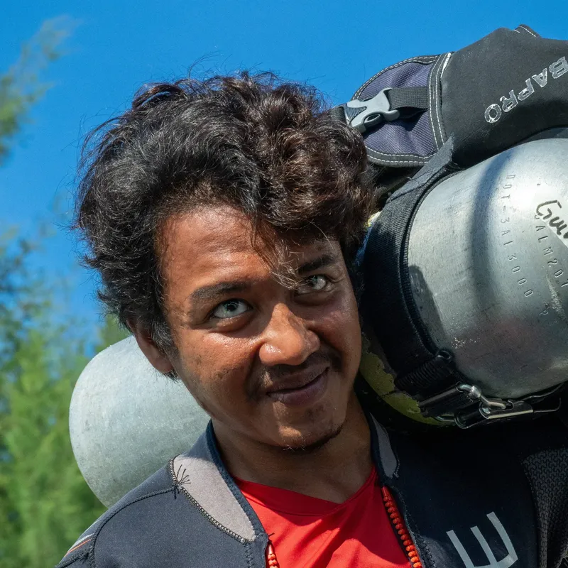 Plongeur souriant avec une bouteille sur son dos en extérieur