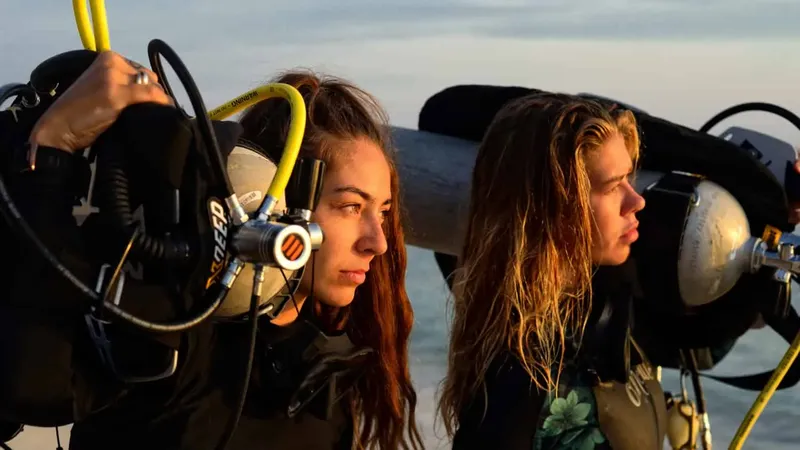 Deux plongeuses équipées regardent au loin, préparation d'une immersion