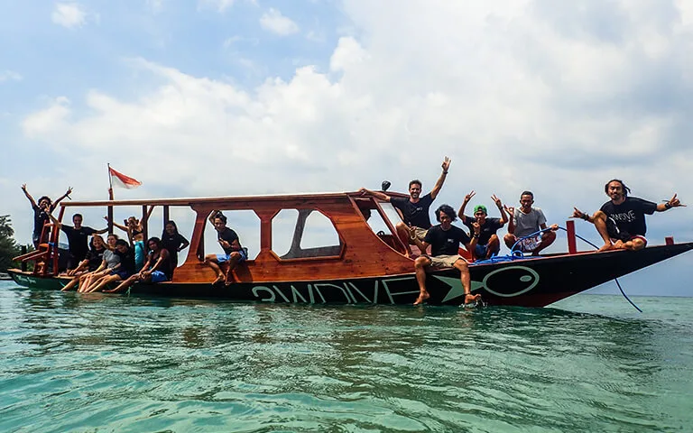 Groupe de personnes souriantes sur un bateau de plongée traditionnel