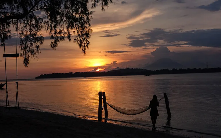 Silhouette d'une personne au bord de l'eau au coucher du soleil