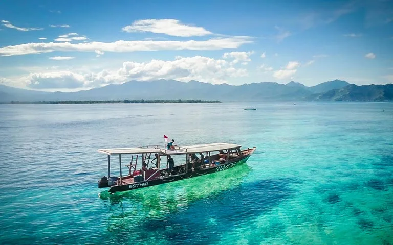Bateau de plongée avec passagers naviguant sur une mer turquoise claire
