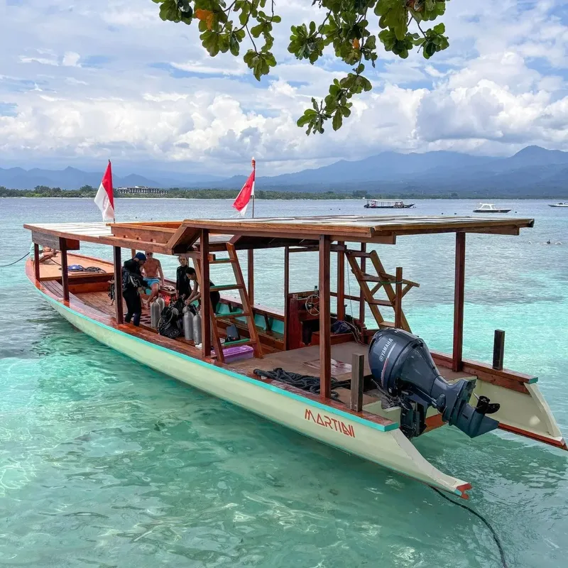 Bateau de plongée traditionnel en bois amarré dans une eau turquoise claire