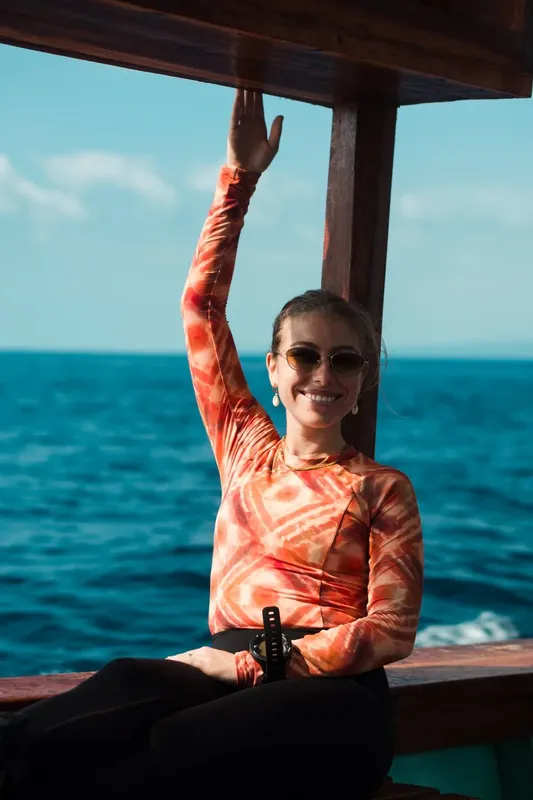 Jeune femme souriante salue depuis un bateau en mer