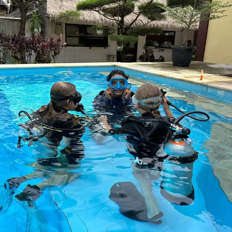 Trois personnes équipées de matériel de plongée dans une piscine