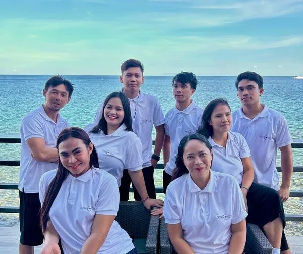 Groupe de personnes souriantes posant devant la mer et le ciel