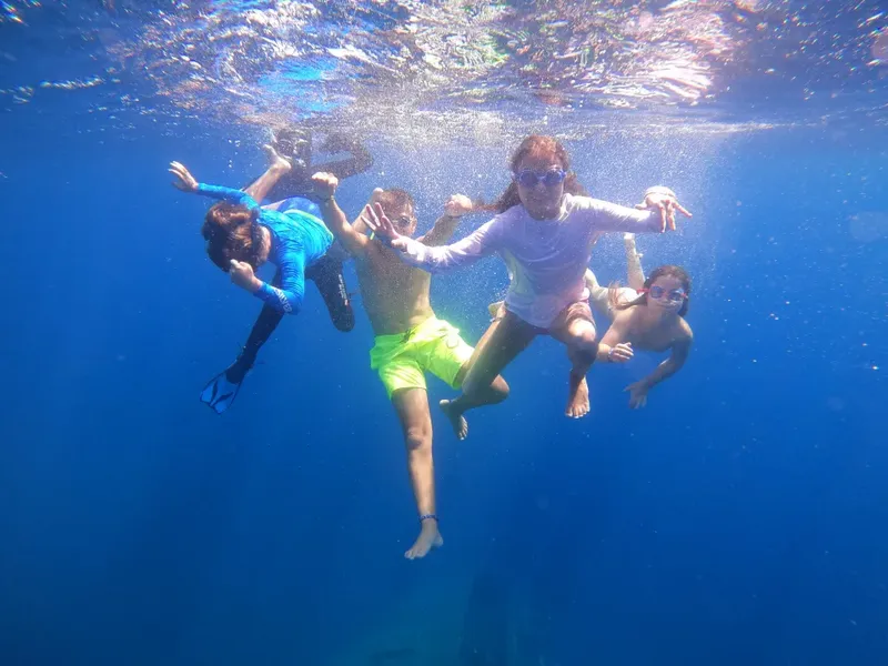 Quatre personnes sourient et nagent librement dans une eau bleue claire