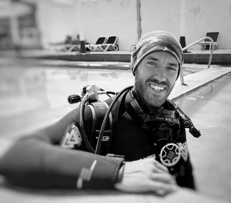 Plongeur souriant en équipement complet près d'une piscine