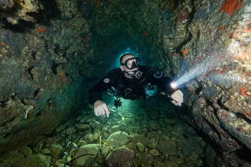 Plongeur explore une grotte sous-marine éclairée par une lampe torche