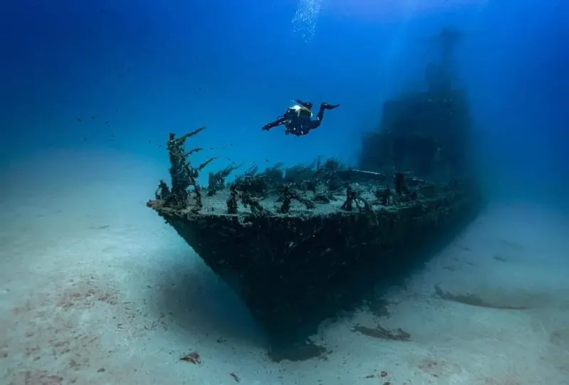 Plongeur explorant l'épave d'un bateau coulé sur fond sableux