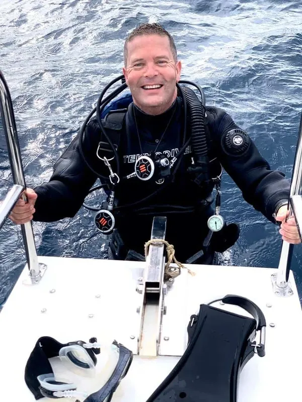 Plongeur souriant sur un bateau, équipé de son matériel de plongée