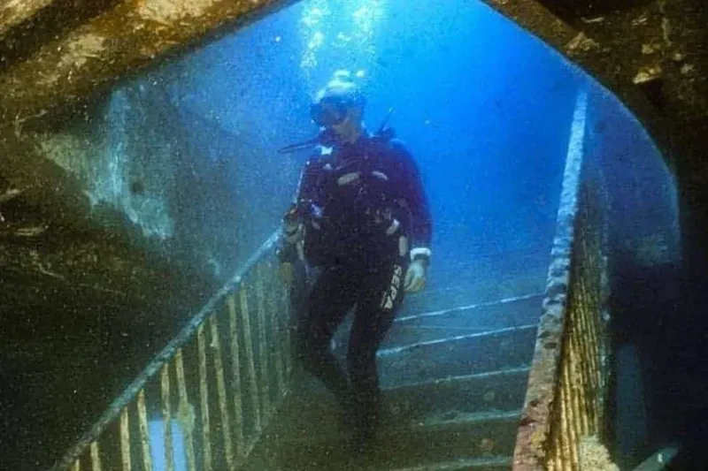 Plongeur descendant un escalier rouillé dans une épave sous-marine