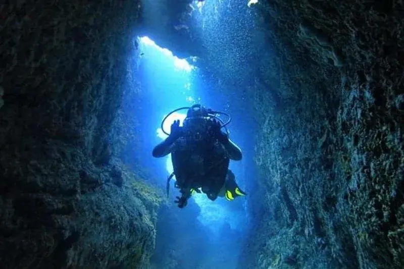 Plongeur explorant une faille sous-marine éclairée par le soleil