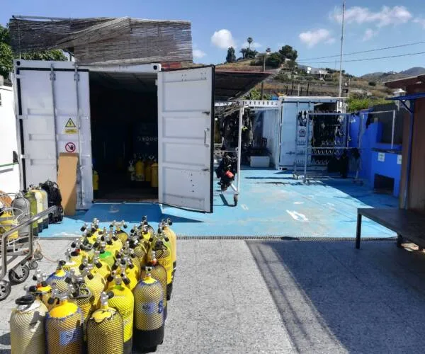 Plongeurs préparant leur matériel devant un conteneur et des bouteilles