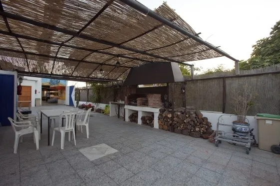 Terrasse ombragée avec tables, chaises, barbecue et espace de stockage bois