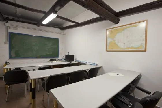 Salle de classe avec tableau noir, bureaux, chaises et carte géographique