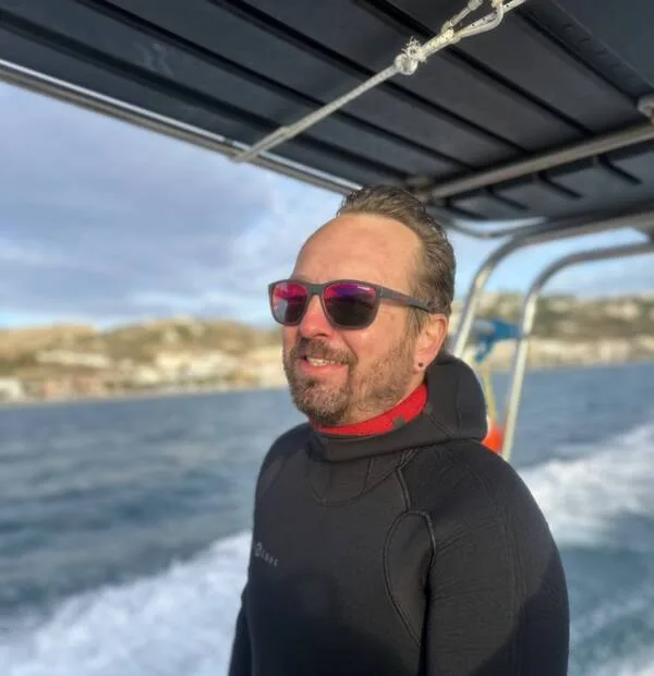 Homme souriant portant une combinaison de plongée et des lunettes de soleil