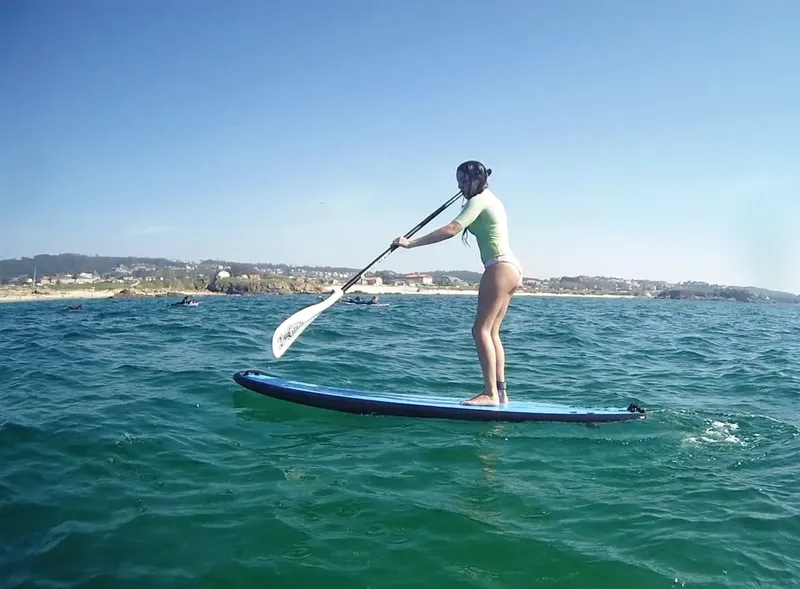 Une femme pratique le stand-up paddle sur une mer turquoise