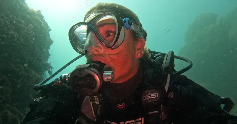 Plongeuse souriante avec masque et détendeur en milieu aquatique