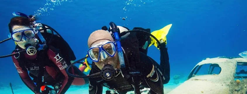 Deux plongeurs explorent un épave sous-marine en bleu profond