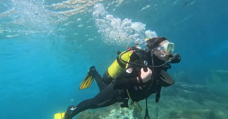 Plongeur en combinaison noire nageant sous l'eau avec son équipement