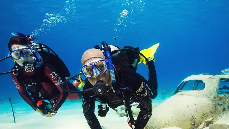 Deux plongeurs sourient face à la caméra dans l'eau bleue