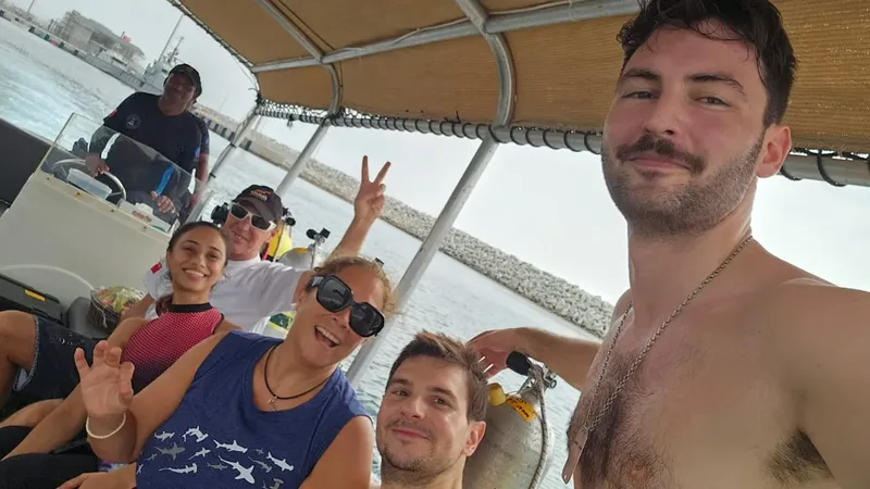 Groupe de plongeurs souriants sur un bateau en mer ensoleillée