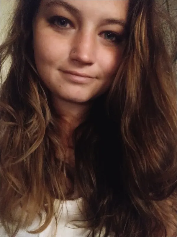 Portrait d'une jeune femme souriante aux cheveux longs et ondulés