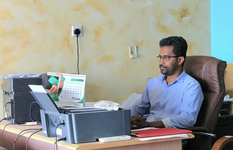Homme assis à un bureau avec un ordinateur et des papiers