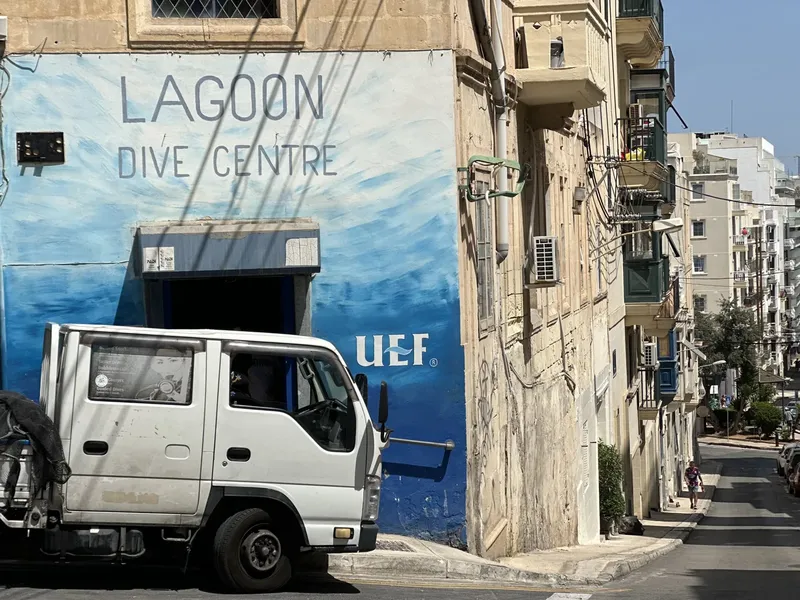 Façade d'un centre de plongée avec un camion et des passants