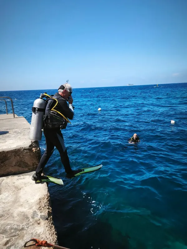 Plongeur s'apprête à entrer dans la mer depuis un quai rocheux