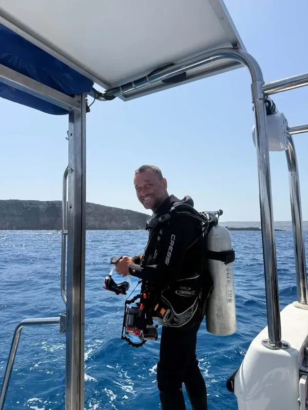 Plongeur souriant sur un bateau, équipé pour une immersion en mer