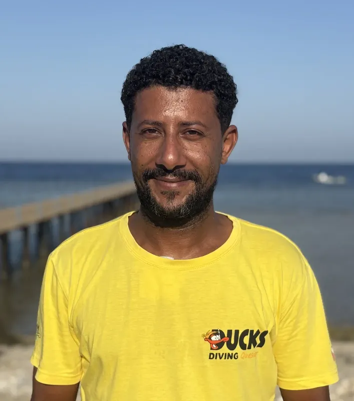 Portrait d'un homme souriant portant un t-shirt jaune avec un logo
