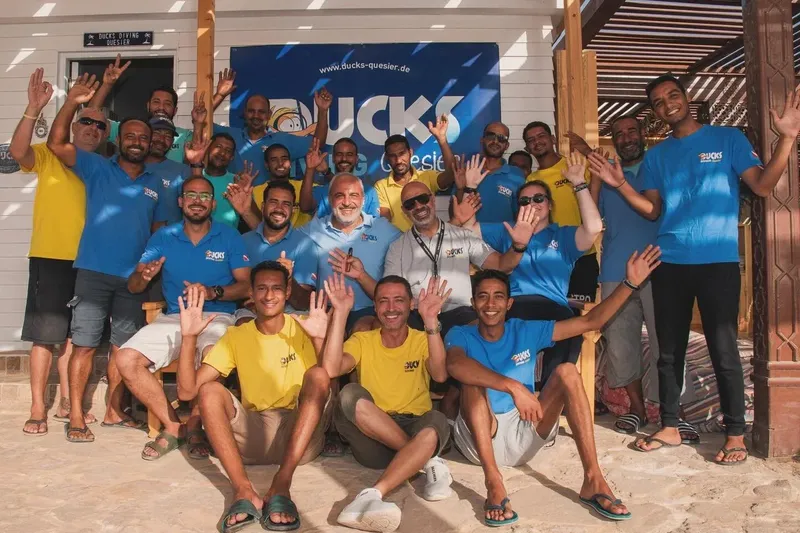 Groupe de personnes souriantes, portant des t-shirts, devant un centre