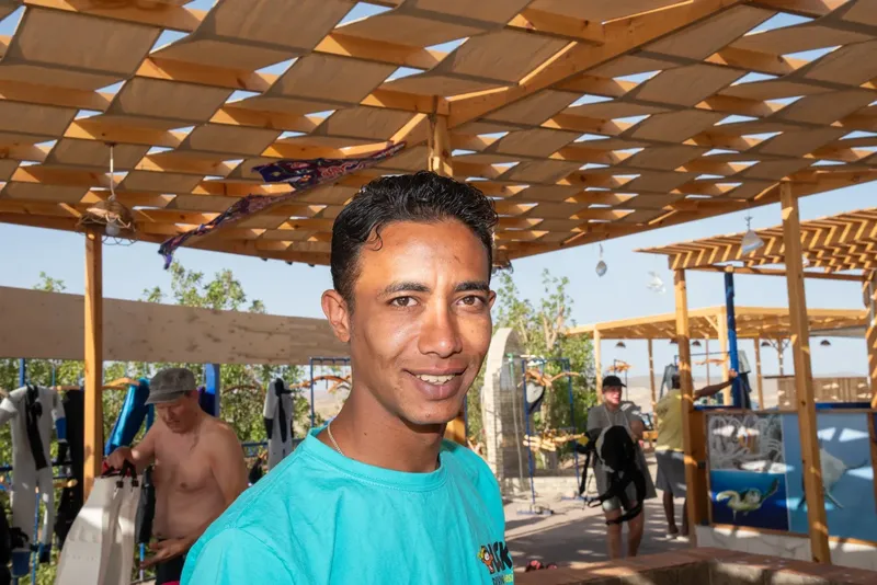 Un homme souriant devant un centre de plongée avec du matériel