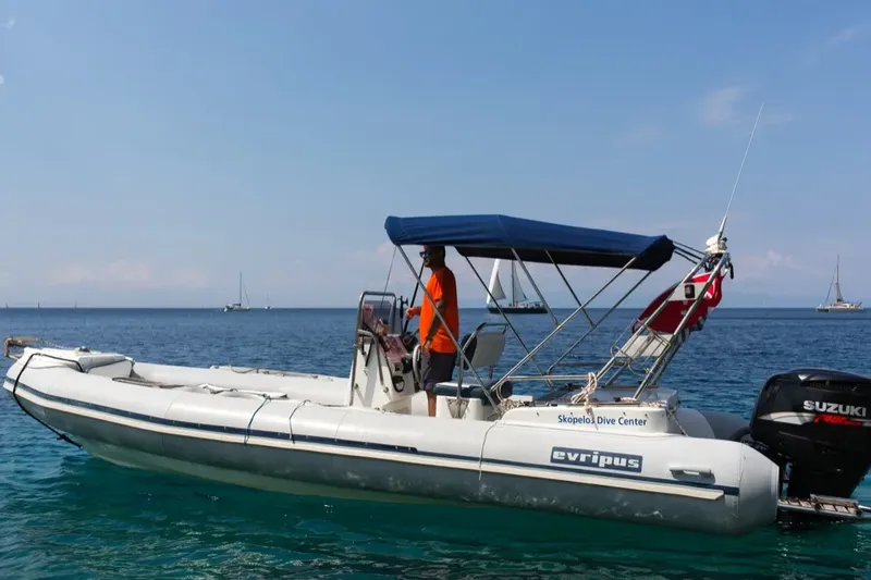Bateau de plongée en mer avec une personne à bord et voiliers