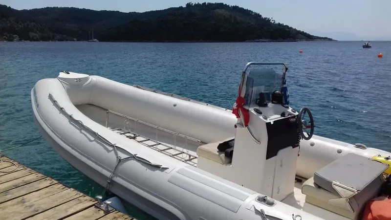 Bateau semi-rigide amarré à un ponton en bois, mer calme et paysage côtier