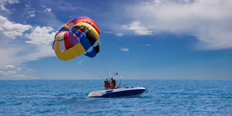 Personnes pratiquant le parachute ascensionnel tirées par un bateau rapide