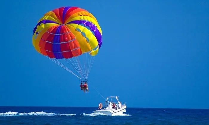 Personnes en parachute ascensionnel tirées par un bateau rapide en mer