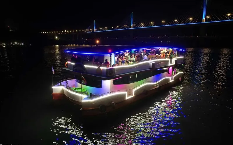 Bateau illuminé naviguant de nuit avec des personnes à bord