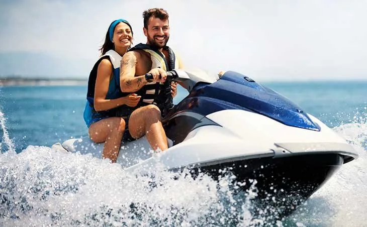 Couple souriant sur un jet ski en pleine mer, amusement