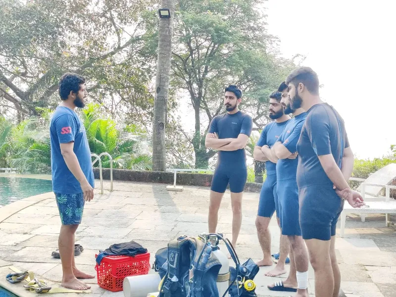 Groupe d'hommes près d'une piscine avec équipement de plongée