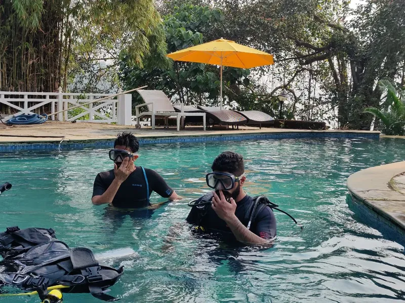 Deux plongeurs en combinaison dans une piscine avec du matériel
