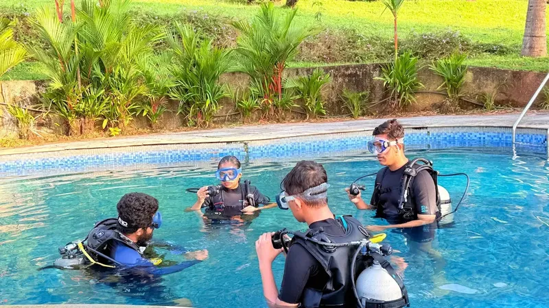 Quatre plongeurs en formation dans une piscine, équipement complet visible