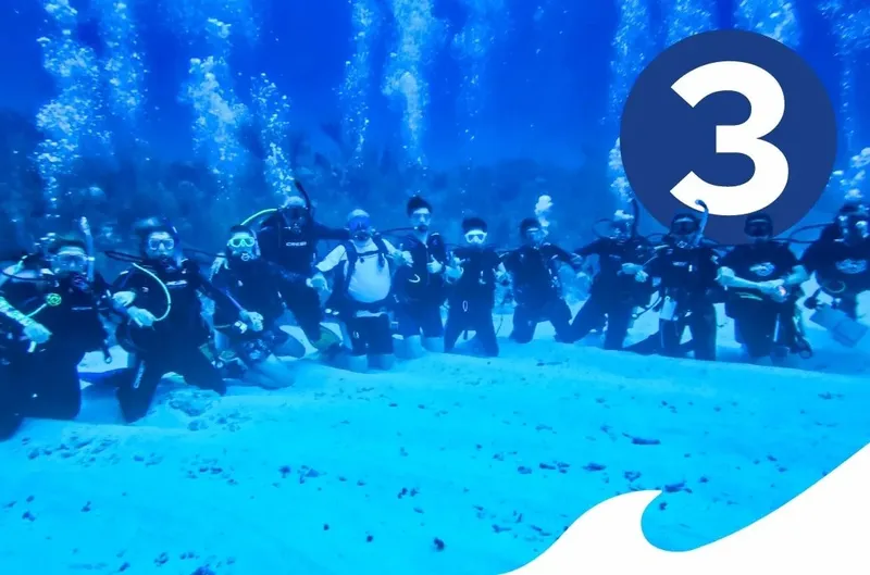 Groupe de plongeurs souriants posant ensemble dans une eau bleue claire